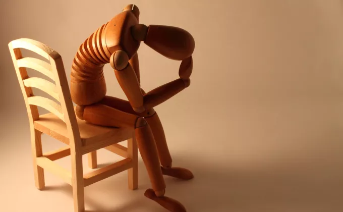 picture of worried sketch dummy sitting in a wooden chair