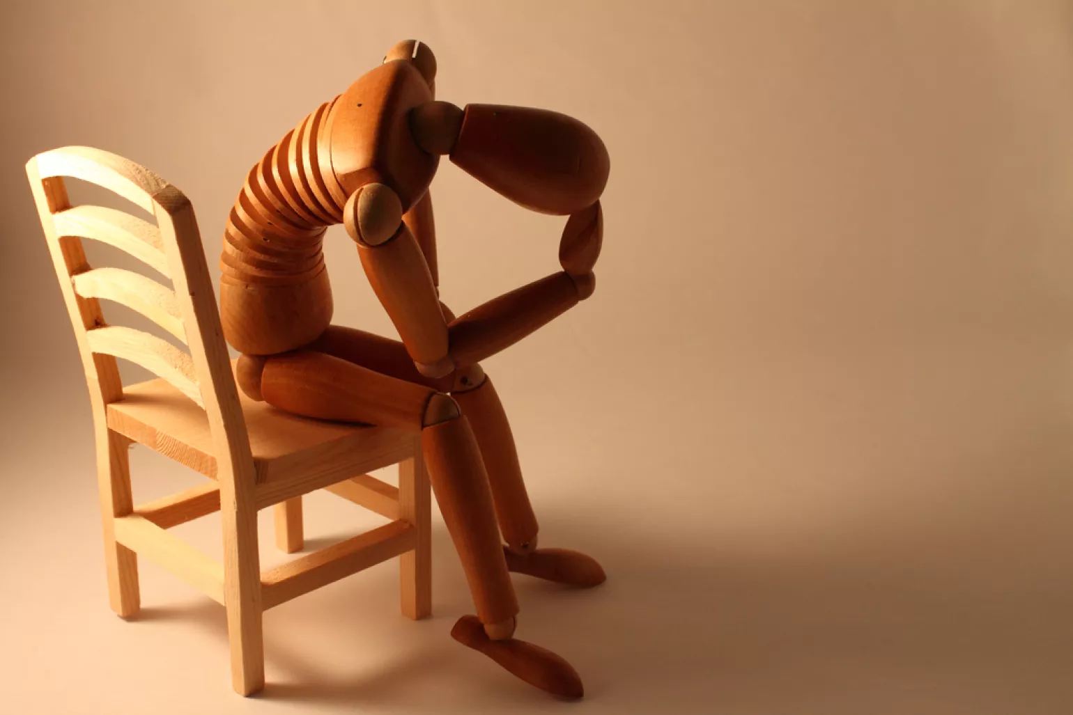 picture of worried sketch dummy sitting in a wooden chair
