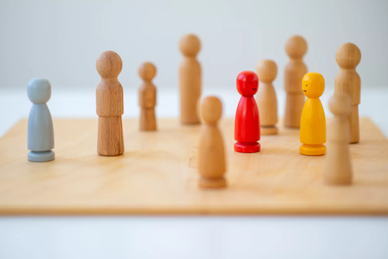 Small wood pawns of on a wood board one gray one red one yellow 