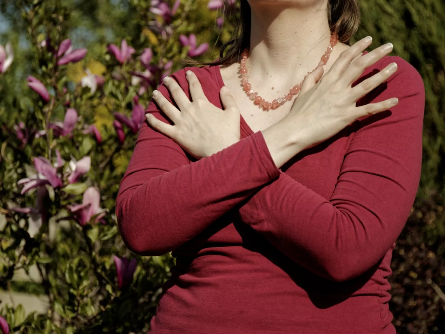 Female with a red shirt touching and tapping her shoulders, crossing hands. Butterfly hug. 