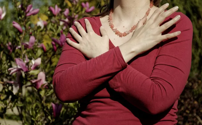 Female with a red shirt touching and tapping her shoulders, crossing hands. Butterfly hug. 